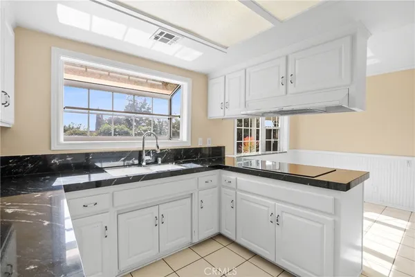 a kitchen with granite countertop white cabinets and a sink