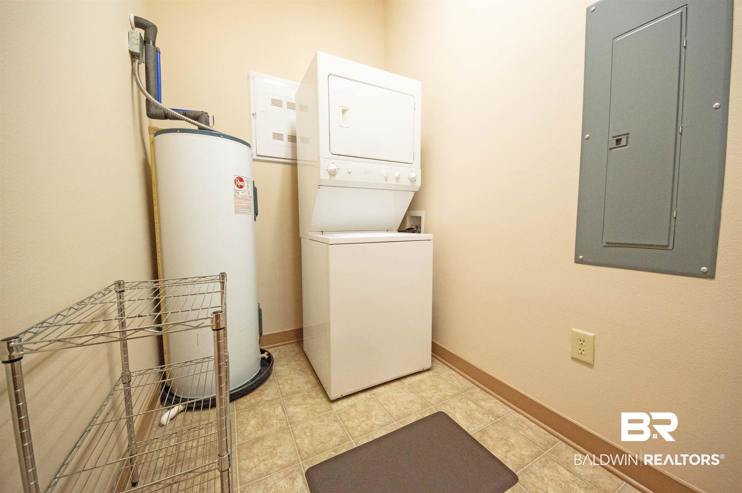 1430 Regency Road, Unit 301C Gulf Shores, AL 36542 - Photo 6 of 22 Washroom with stacked washer and dryer, light tile patterned flooring, electric water heater, and electric panel