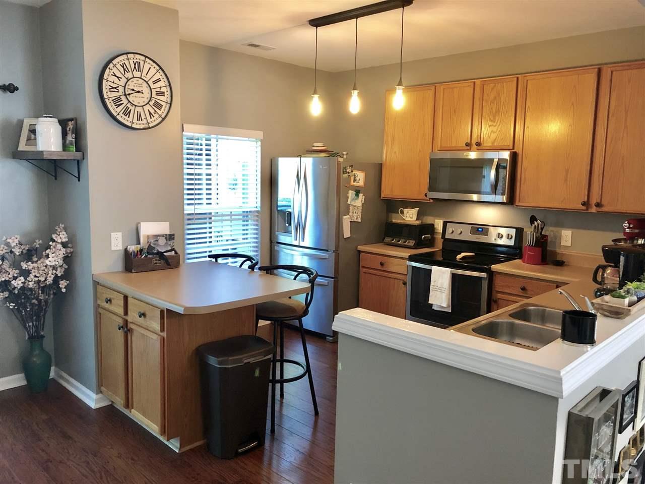 8126 Rhiannon Road Raleigh, NC 27613 - Photo 11 of 24 a kitchen with kitchen island stainless steel appliances a stove refrigerator a sink a dining table and chairs