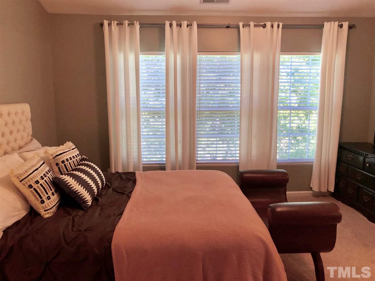 8126 Rhiannon Road Raleigh, NC 27613 - Photo 15 of 24 a bedroom with a bed and a couch next to a window
