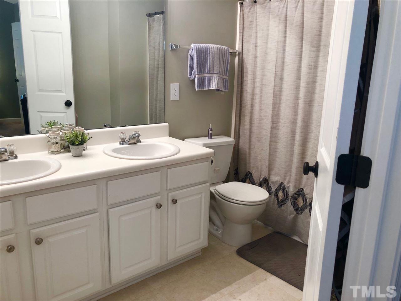 8126 Rhiannon Road Raleigh, NC 27613 - Photo 17 of 24 a bathroom with a toilet a sink and mirror