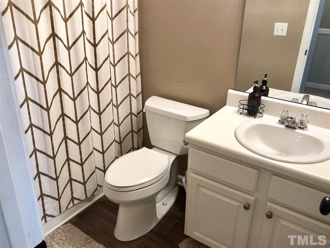 8126 Rhiannon Road Raleigh, NC 27613 - Photo 20 of 24 a white toilet sitting next to a white sink and a mirror