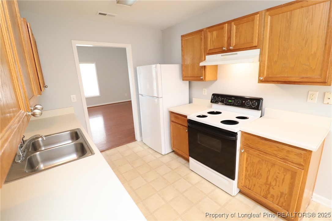 4105 Scofield Drive Raleigh, NC 27610 - Photo 6 of 27 a kitchen with stainless steel appliances a stove a sink and a refrigerator with wooden floor