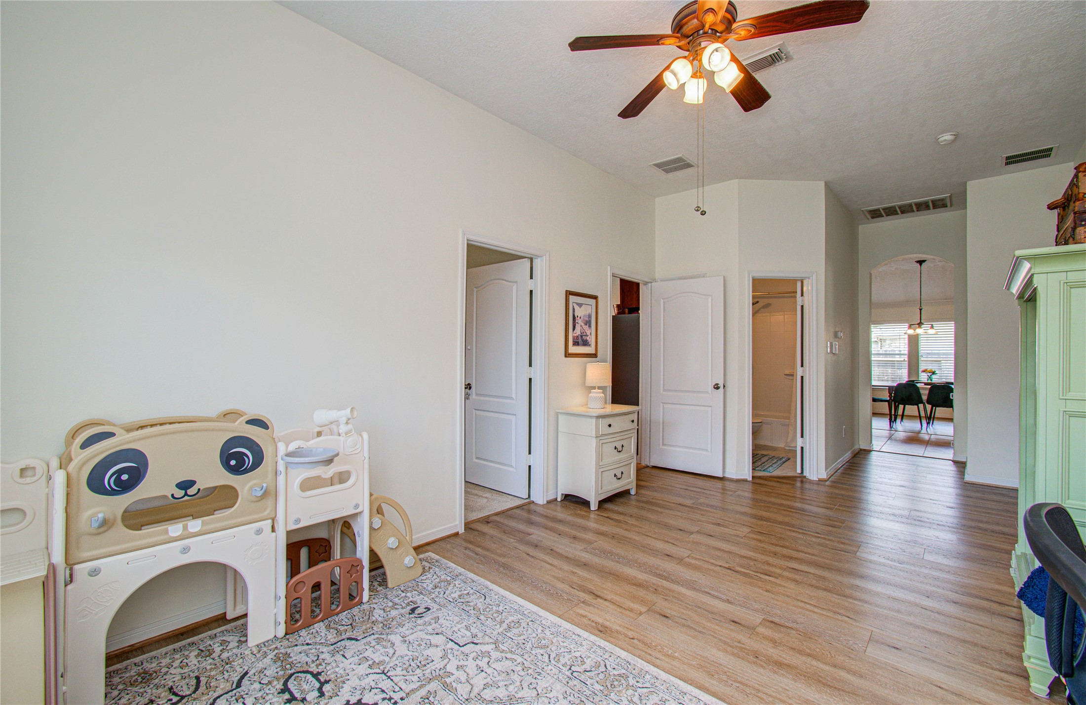 20007 Alcea Court Spring, TX 77379 - Photo 20 of 36 This bright room features wood flooring, a ceiling fan, and a playful children's playset. It connects seamlessly to additional living spaces and has access to a bathroom, making it versatile for various uses.