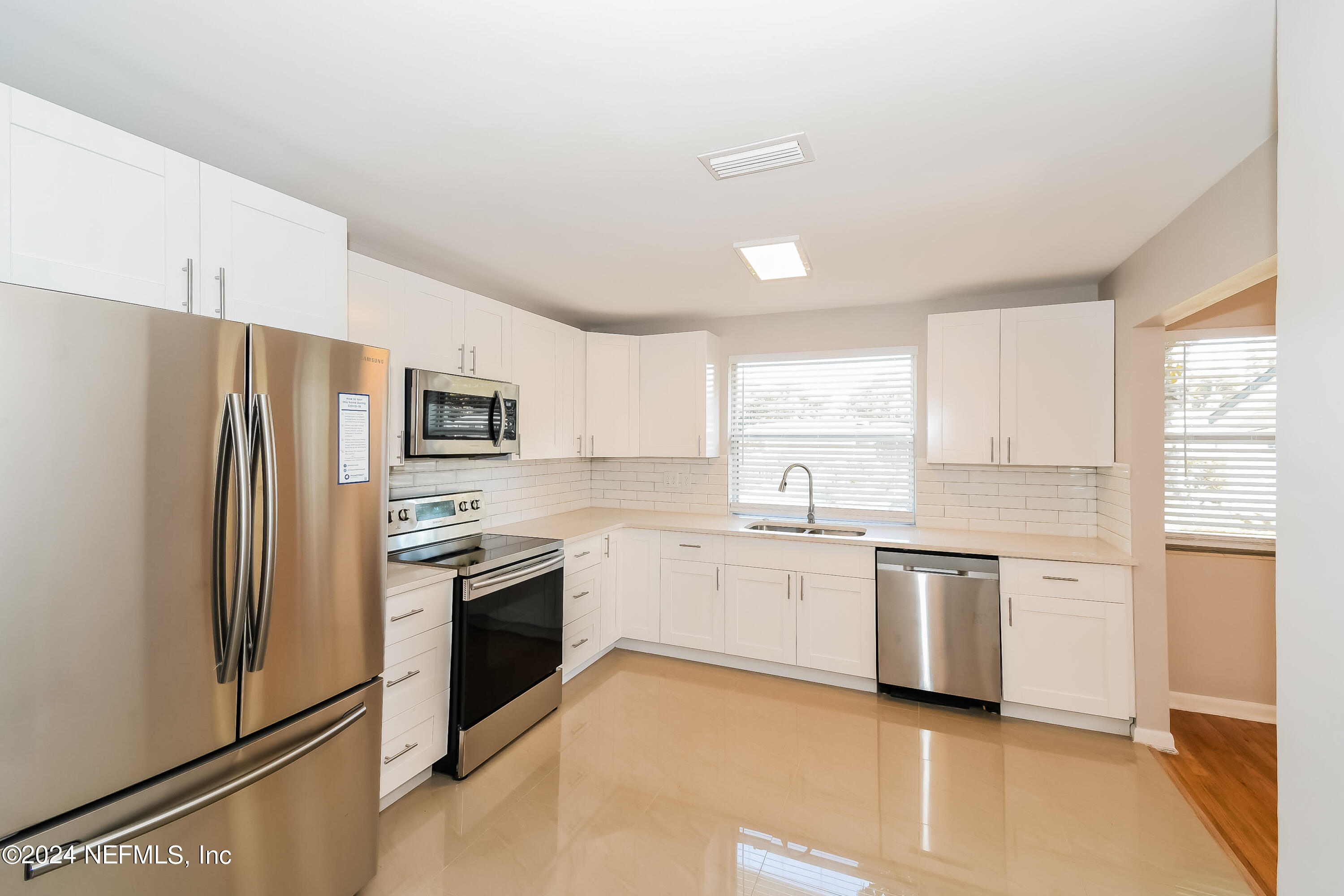 7070 Perke Drive Jacksonville, FL 32210 - Photo 3 of 16 a kitchen with white cabinets and stainless steel appliances
