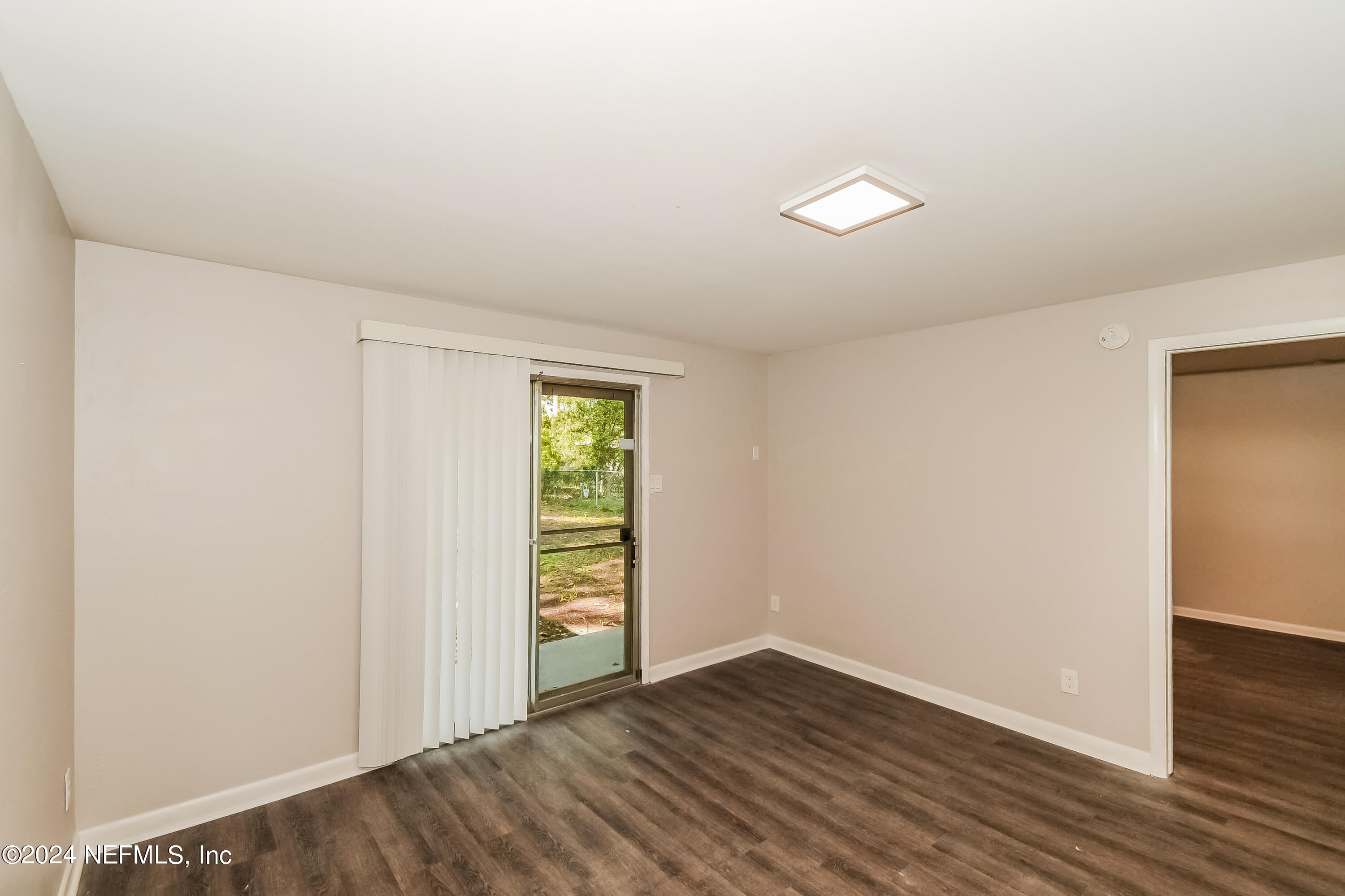 7070 Perke Drive Jacksonville, FL 32210 - Photo 6 of 16 an empty room with wooden floor and windows