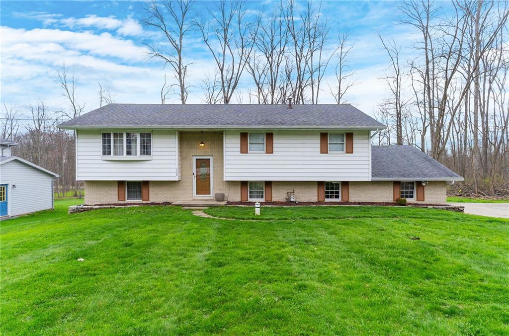 a house that is sitting in the grass with large trees