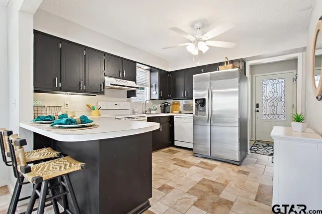 a kitchen with stainless steel appliances a refrigerator a sink a stove a dining table and chairs