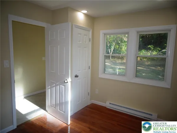 a view of hallway with window and wooden floor