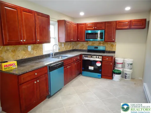 a kitchen with stainless steel appliances granite countertop a stove a sink and a microwave