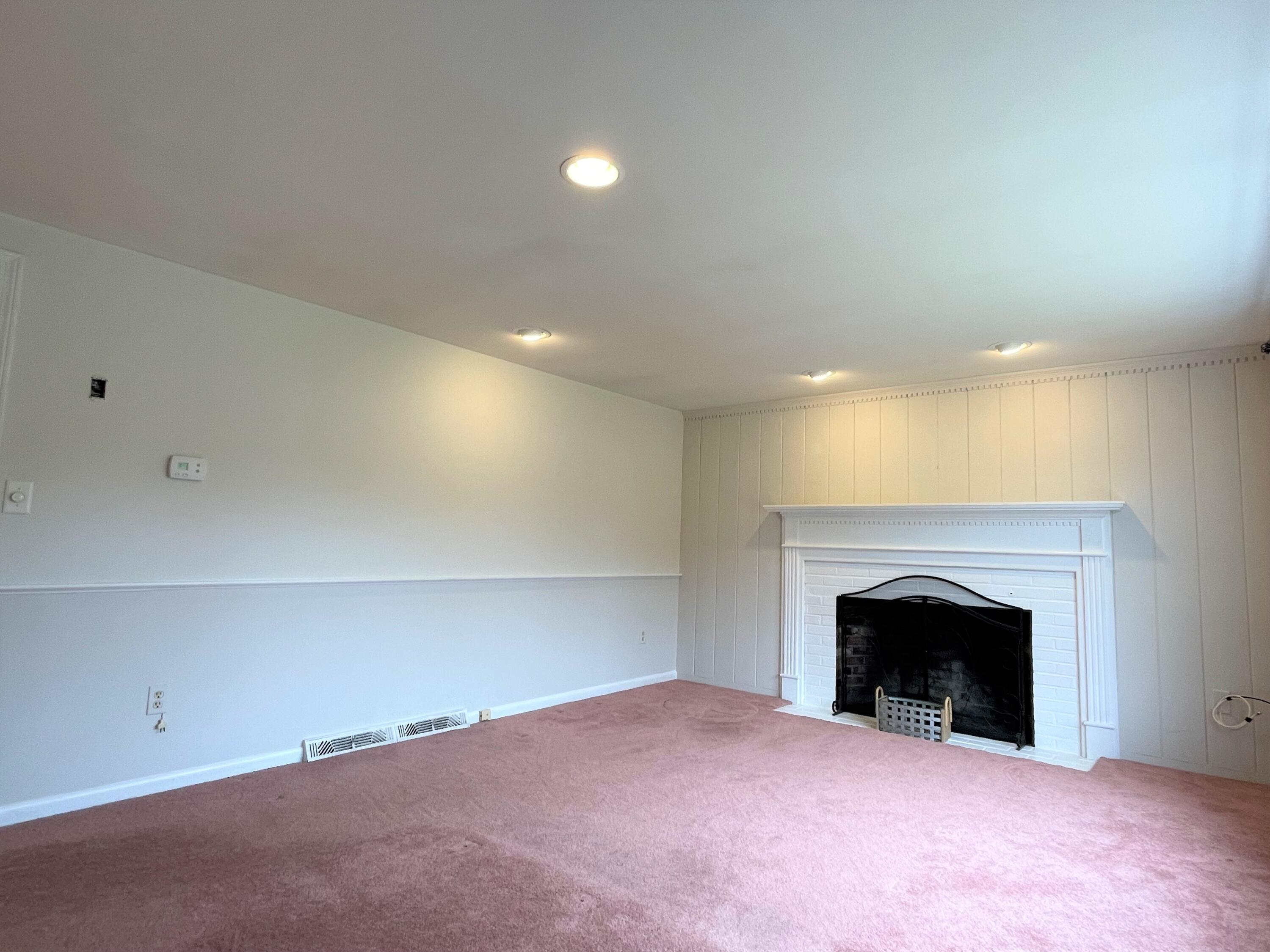 21 Long Road Harwich, MA 02645 - Photo 8 of 18 an empty room with a fireplace and chandelier fan