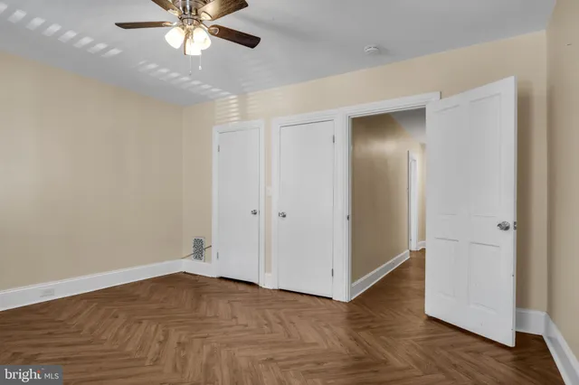an empty room with wooden floor closet and fan