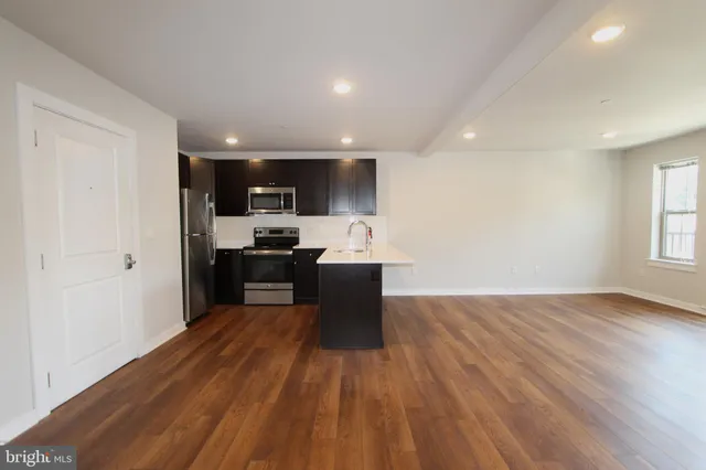 a kitchen with kitchen island wooden floors appliances and a window