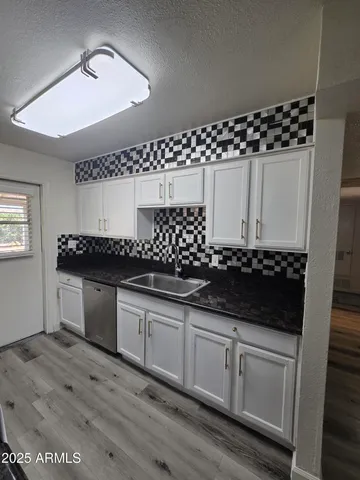 a kitchen with granite countertop a white cabinets and a sink