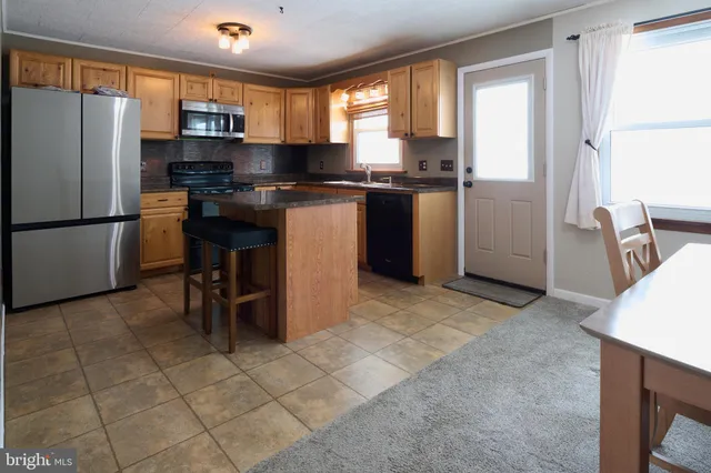 a kitchen with stainless steel appliances granite countertop a stove a refrigerator a sink and a microwave