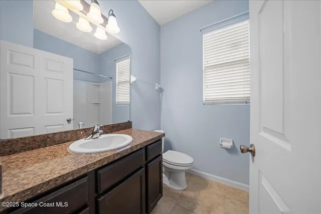 a bathroom with a granite countertop sink toilet and a mirror