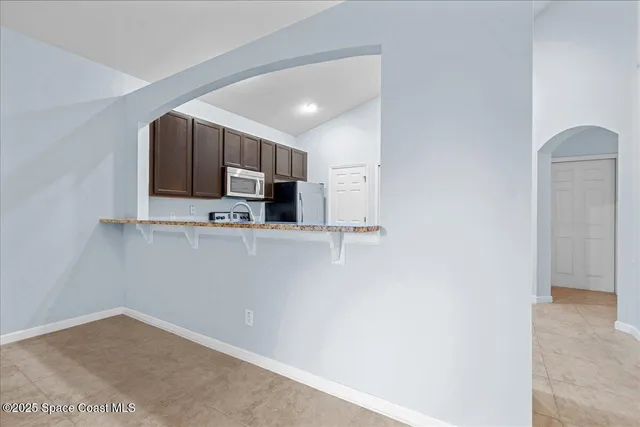 a view of kitchen with stainless steel appliances granite countertop white cabinets and a refrigerator
