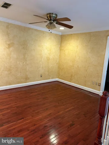 a view of room with wooden floor and a ceiling fan