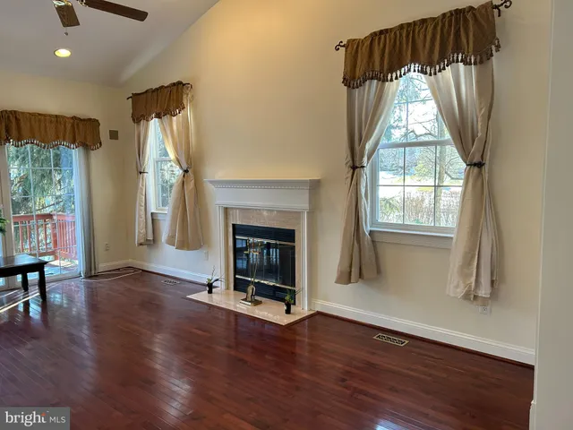 a view of a livingroom with wooden floor a fireplace and window