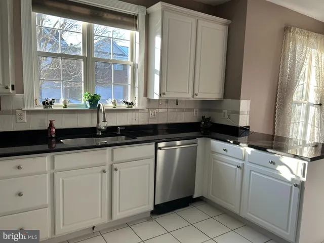 a kitchen with granite countertop a sink and a white wooden cabinets