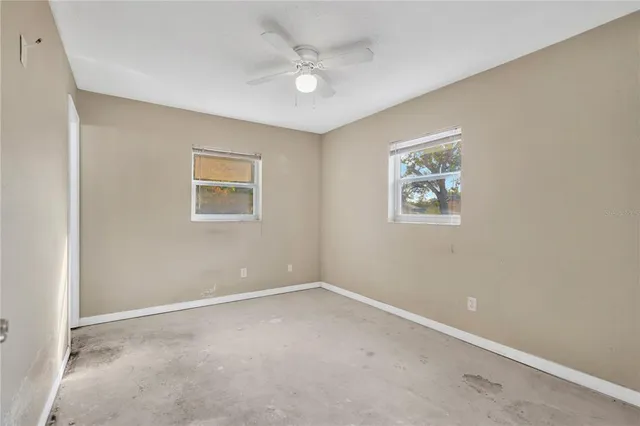 an empty room with windows and fan