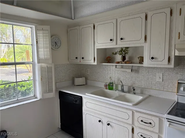 a kitchen with stainless steel appliances white cabinets and a window