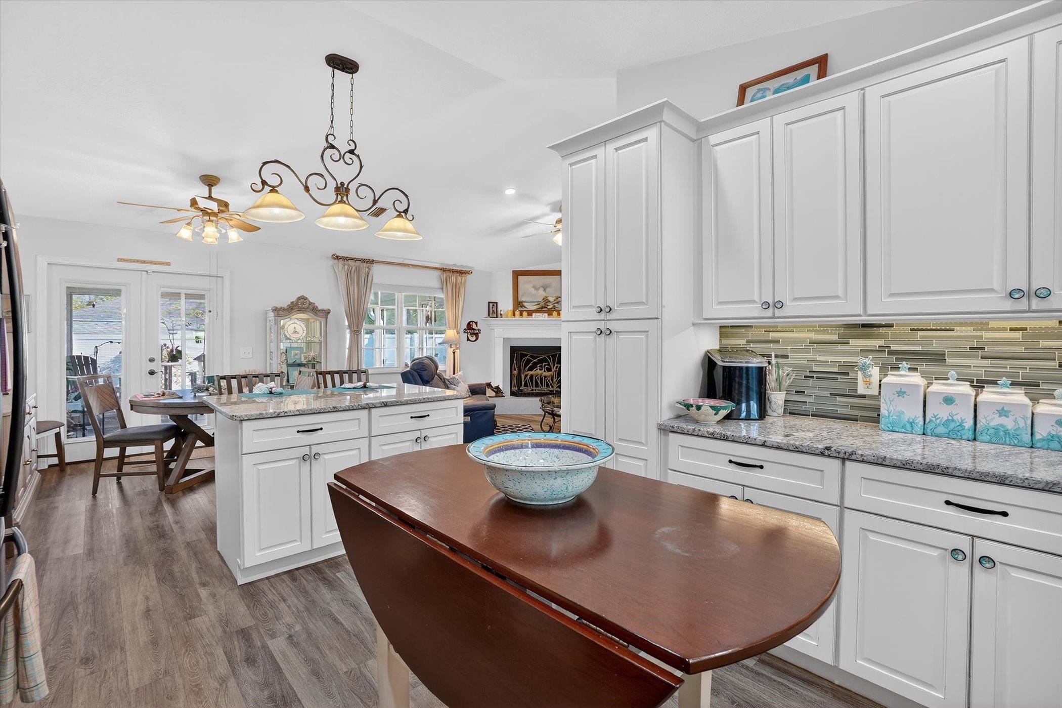 229 Yale Road St. Augustine, FL 32086 - Photo 2 of 47 Kitchen with light stone counters, white cabinets, a ceiling fan, a fireplace, and tasteful backsplash