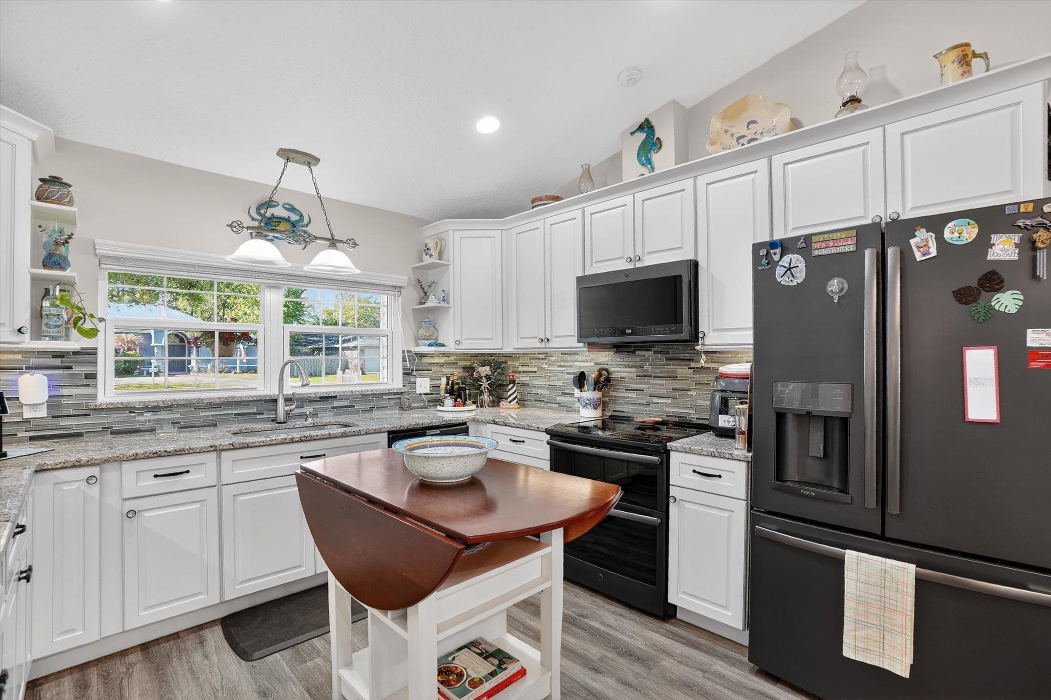 229 Yale Road St. Augustine, FL 32086 - Photo 4 of 47 Kitchen featuring stainless steel refrigerator with ice dispenser, open shelves, white cabinetry, light stone countertops, and vaulted ceiling