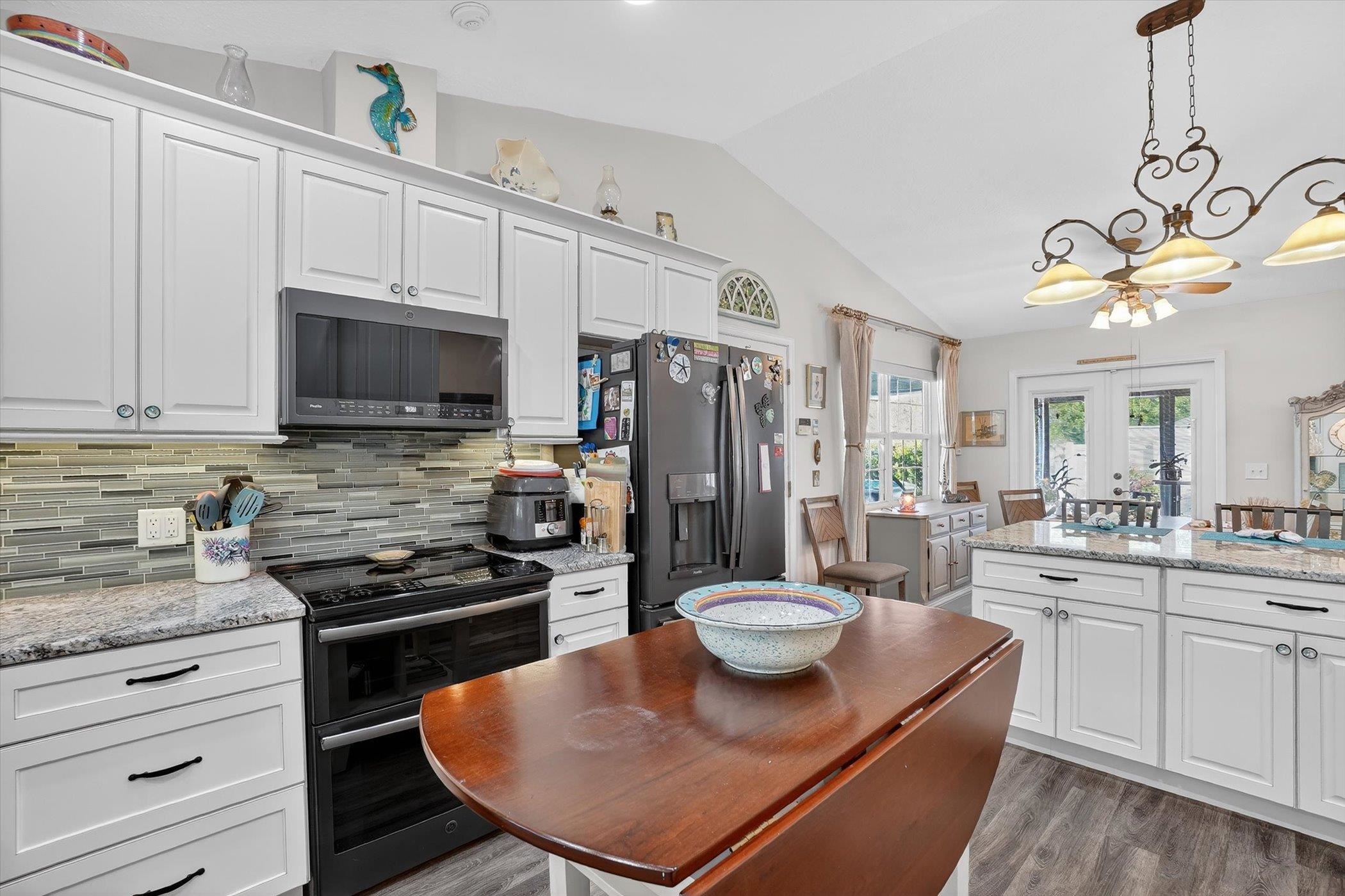 229 Yale Road St. Augustine, FL 32086 - Photo 5 of 47 Kitchen with stainless steel appliances, light stone counters, white cabinets, lofted ceiling, and pendant lighting