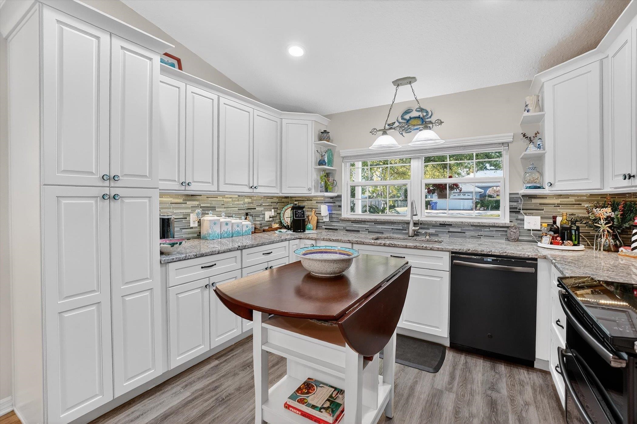 229 Yale Road St. Augustine, FL 32086 - Photo 7 of 47 Kitchen with open shelves, light stone counters, black appliances, and lofted ceiling