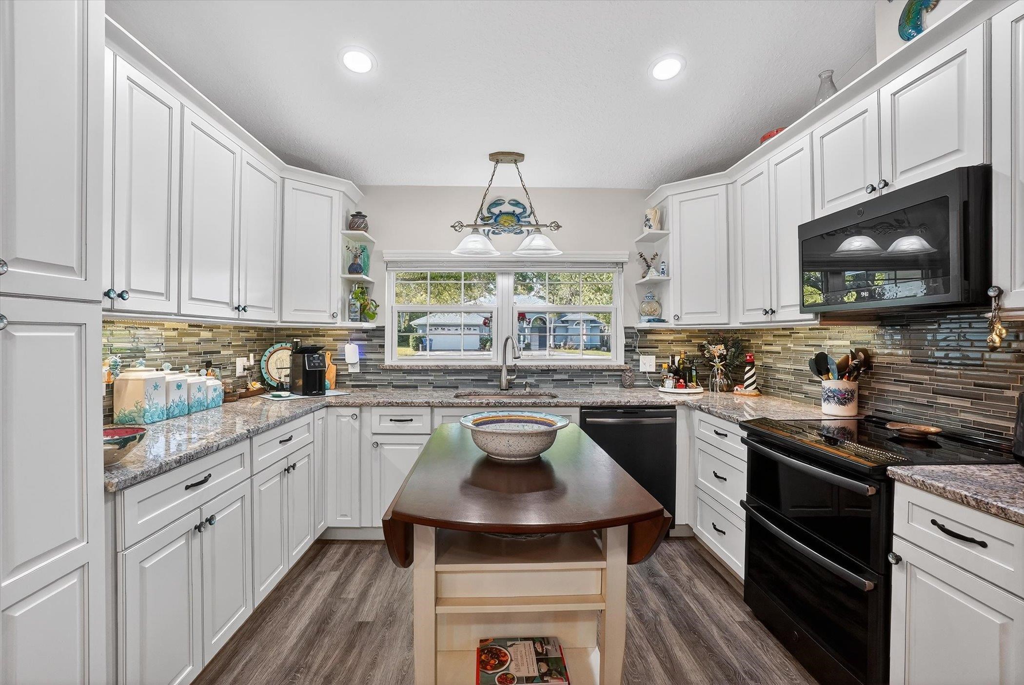 229 Yale Road St. Augustine, FL 32086 - Photo 8 of 47 Kitchen with open shelves, black appliances, light stone counters, and white cabinetry