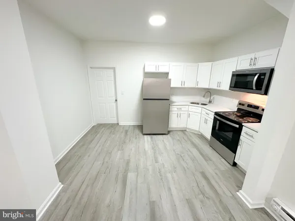 a kitchen with a sink wooden floor and stainless steel appliances