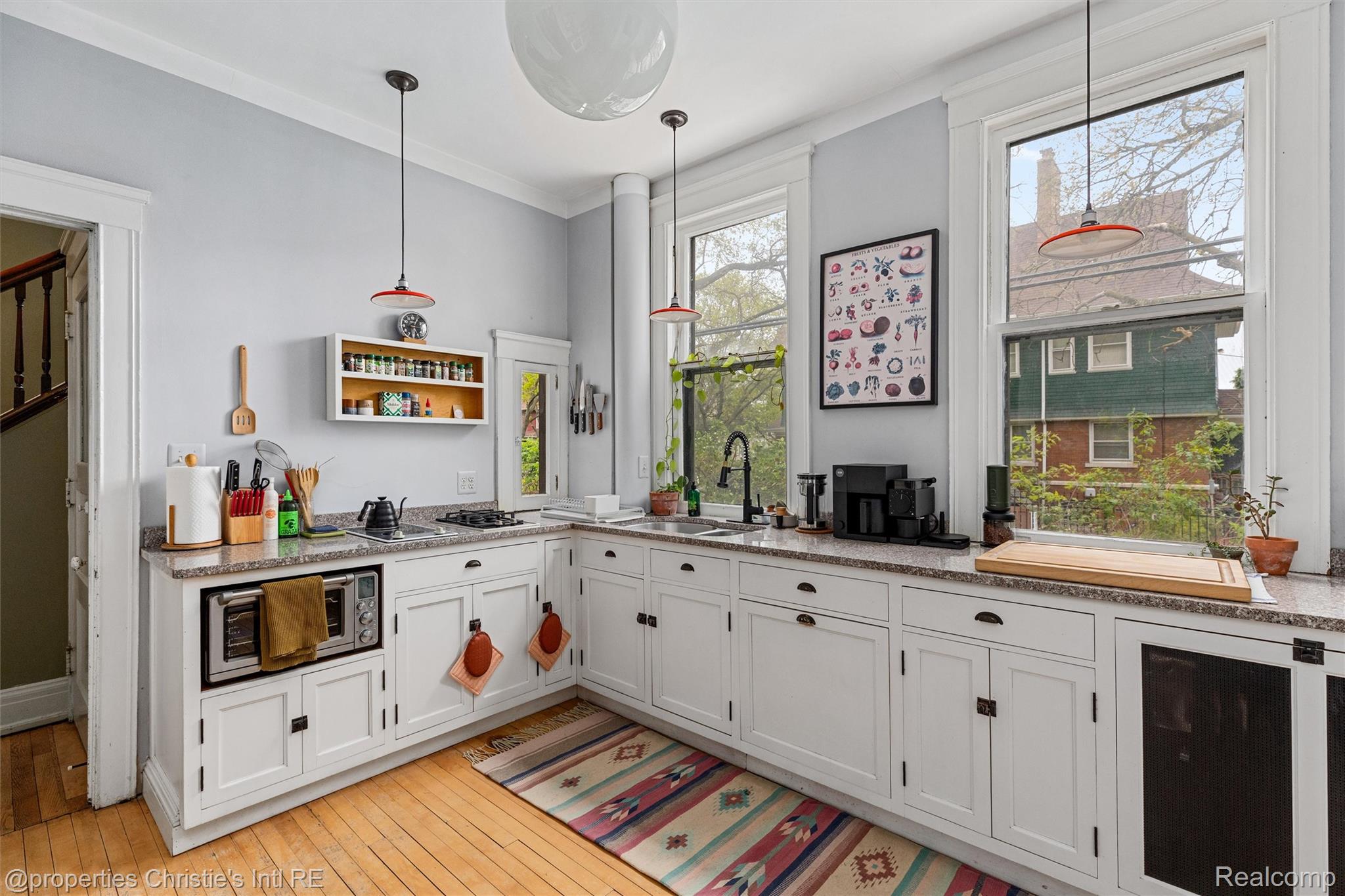 36 Longfellow Street Detroit, MI 48202 - Photo 20 of 81 Kitchen featuring white cabinets, decorative light fixtures, crown molding, stainless steel microwave, and light wood-type flooring