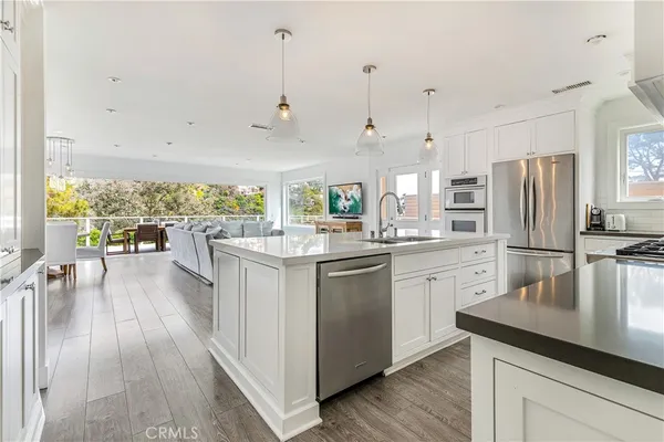 a kitchen with stainless steel appliances a lot of white cabinets and wooden floors