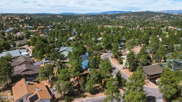 an aerial view of residential houses with outdoor space and trees