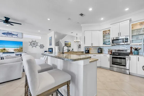 a open kitchen with stainless steel appliances granite countertop a stove top oven a sink dishwasher and white cabinets with wooden floor