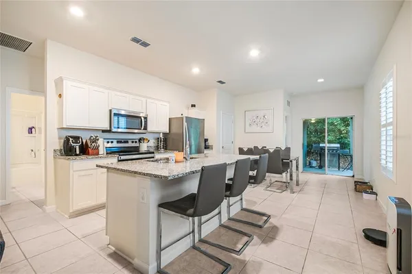 a living room with stainless steel appliances a stove a sink a counter top space and cabinets