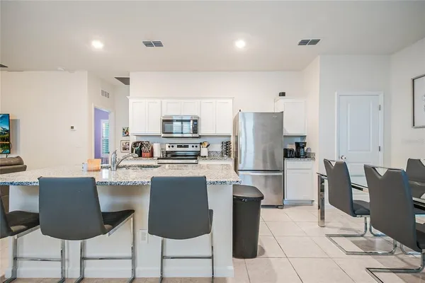 a kitchen with stainless steel appliances a dining table chairs stove refrigerator and cabinets