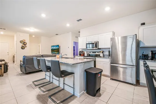 a kitchen with stainless steel appliances a refrigerator a stove a sink a dining table and chairs
