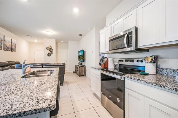 a kitchen with stainless steel appliances granite countertop a stove top oven a sink a counter space and cabinets
