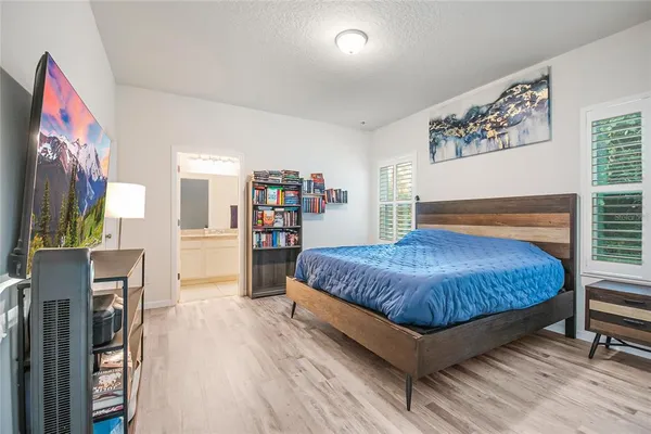 a bedroom with a large bed a flat tv screen and a book shelf