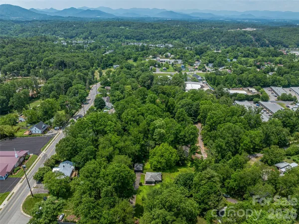 an aerial view of residential house with outdoor space and trees all around