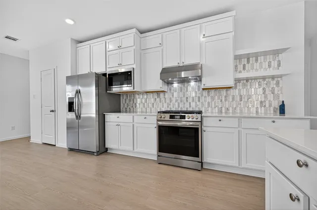 a kitchen with stainless steel appliances white cabinets and a stove