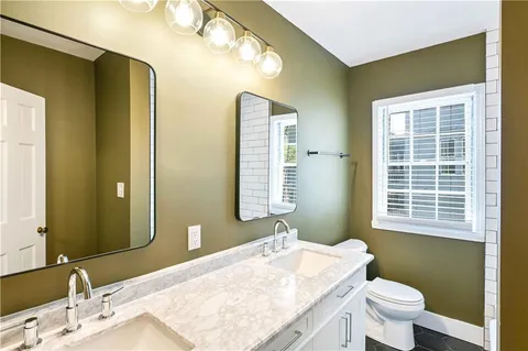 a bathroom with a granite countertop sink a toilet and mirror