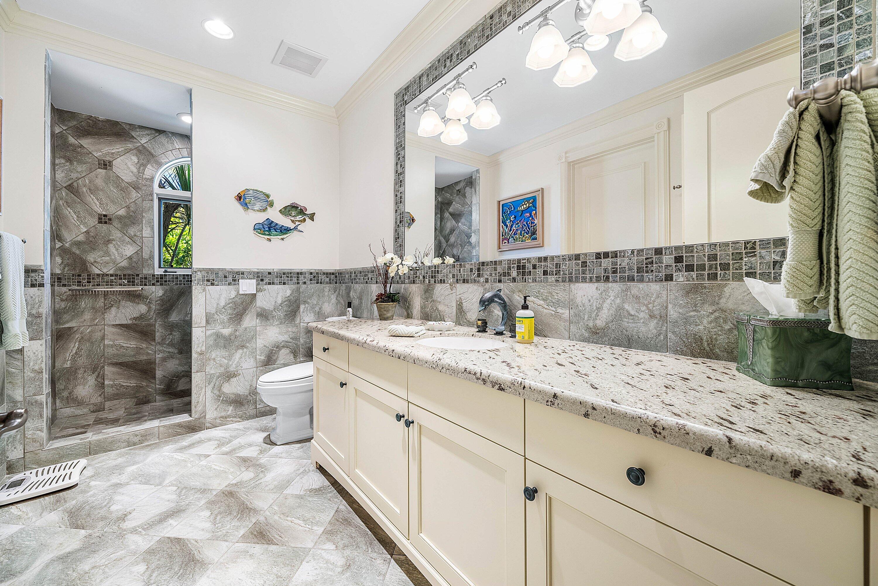 6381 Southeast Harbor Circle Stuart, FL 34996 - Photo 29 of 102 a bathroom with a granite countertop sink a toilet a mirror and shower