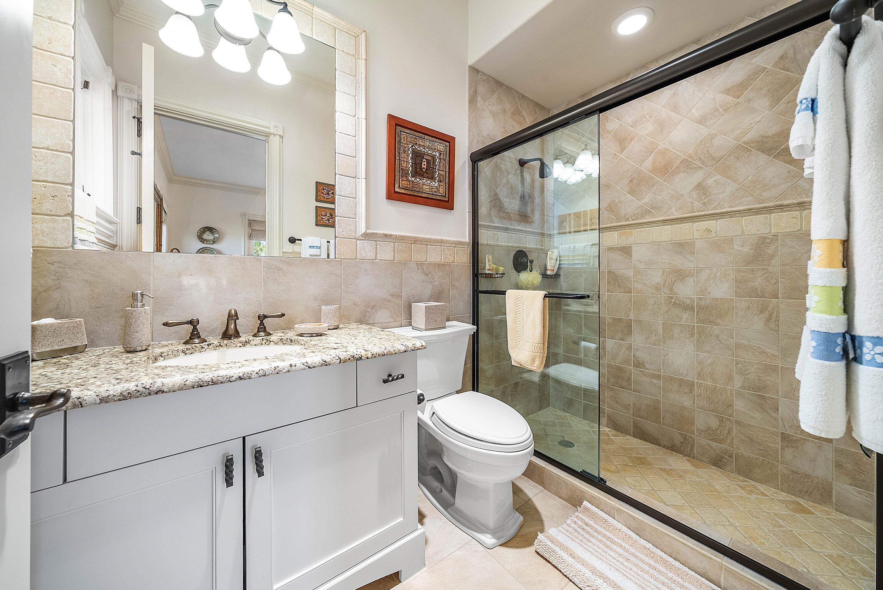 6381 Southeast Harbor Circle Stuart, FL 34996 - Photo 55 of 102 a bathroom with a granite countertop sink toilet a mirror and shower