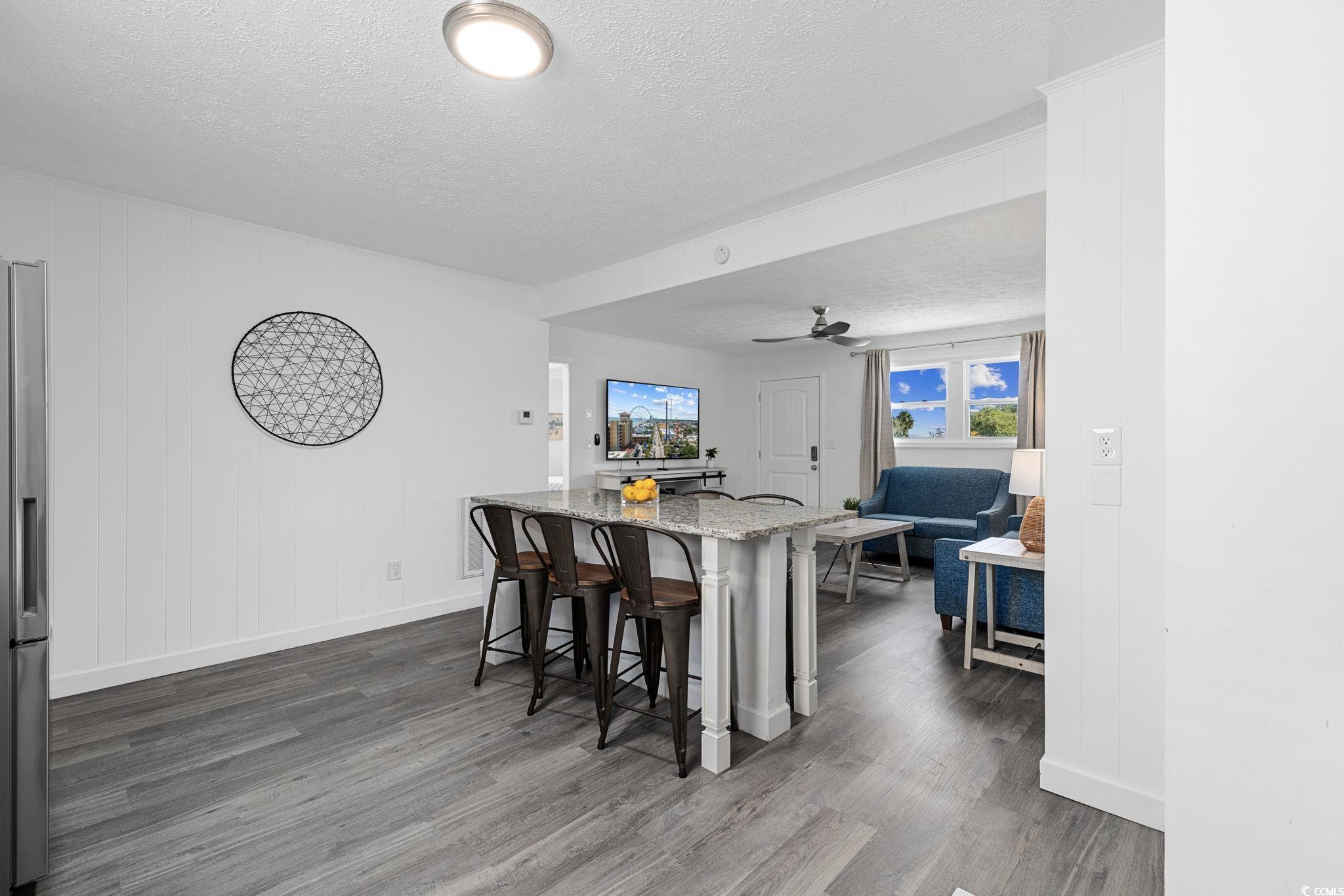 409 17th Avenue North, Unit 1 Myrtle Beach, SC 29577 - Photo 15 of 26 Kitchen with a textured ceiling, light stone countertops, a breakfast bar area, dark wood-type flooring, and ceiling fan