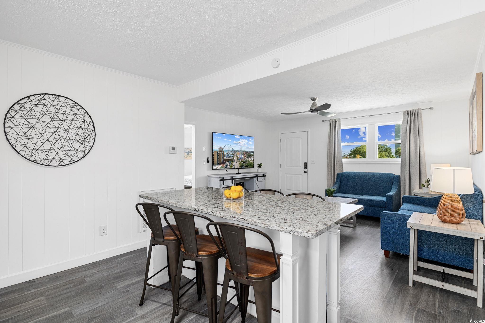 409 17th Avenue North, Unit 1 Myrtle Beach, SC 29577 - Photo 9 of 26 Kitchen with a kitchen breakfast bar, dark wood-type flooring, a textured ceiling, light stone countertops, and ceiling fan