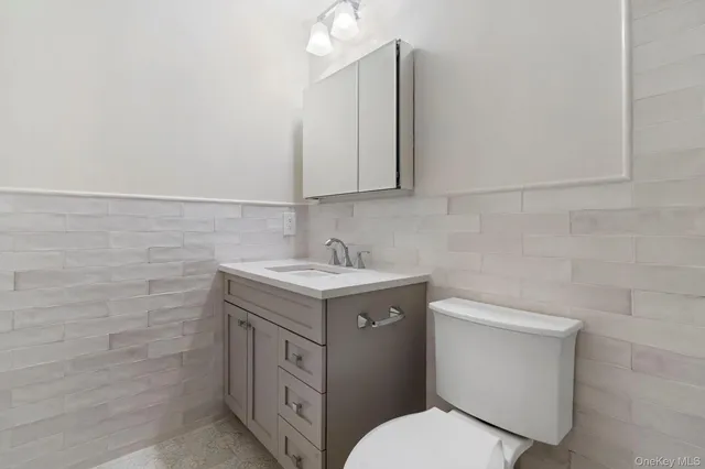 a bathroom with a granite countertop toilet sink and mirror
