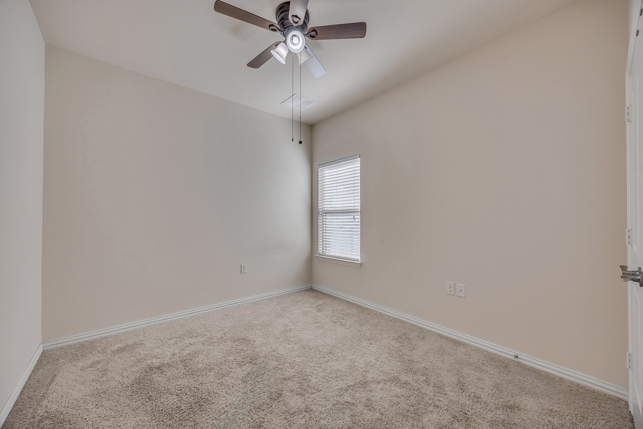 7212 Vail Ridge Street Austin, TX 78744 - Photo 12 of 26 A comfortable bedroom features plush carpeting, a single window with blinds, and a practical ceiling fan for year-round comfort.